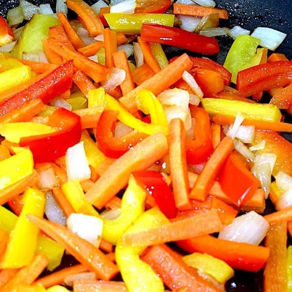 Onions, carrots and bell pepper being sautéed for chicken-ramen stir-fry